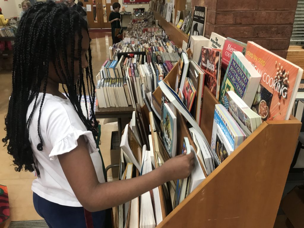 An elementary school student looks at books during an annual Book Sale event at Cambridge Friends School